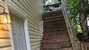 A wooden staircase with a metal railing leading to a deck.
