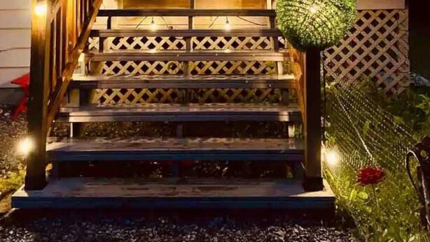 A house with a wooden deck, a staircase, and string lights. - Welcome to Kozykave (Kawartha Lakes)