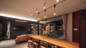 A modern dining area with a wooden table, chairs, and pendant lighting. - Reflexion Villas GLANZ (Nago)