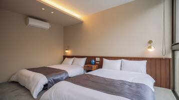 A hotel room with two beds, a wooden headboard, a nightstand with a lamp, and an air conditioning unit.