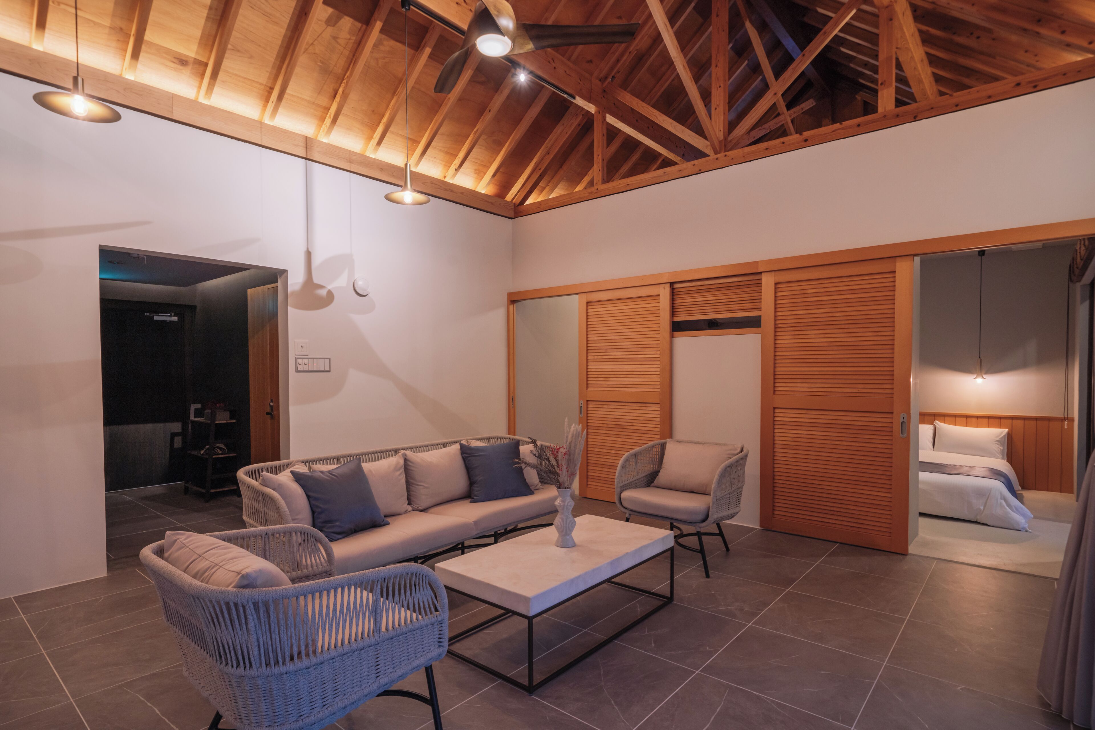Ein modernes Interieur mit einer Couch, Sesseln, einem Couchtisch und einer Holzbalkendecke.