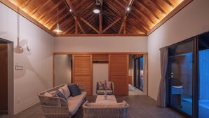 A modern interior with a high ceiling, wicker furniture, and a view through a glass door. - Reflexion Villas GLANZ (Nago)