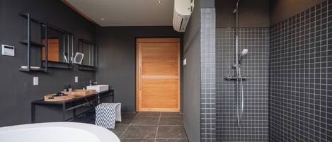 Un baño moderno con una bañera independiente, un tocador con espejo y una zona de ducha con cabezal de ducha de lluvia.
