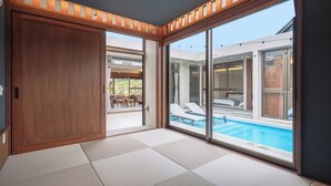A modern room with tatami mats, large sliding glass doors leading to a pool area. - Reflexion Villas GLANZ (Nago)