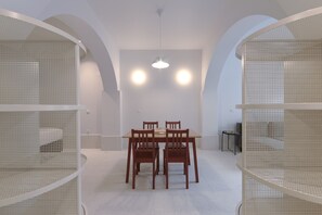 Een eethoek met een ronde tafel en vier stoelen, omgeven door witte muren en gewelfde plafonds.