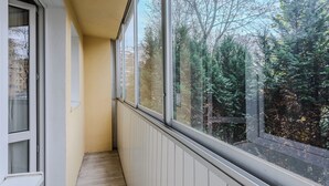 Un pasillo estrecho con ventanas amplias, suelo de madera y pared blanca.