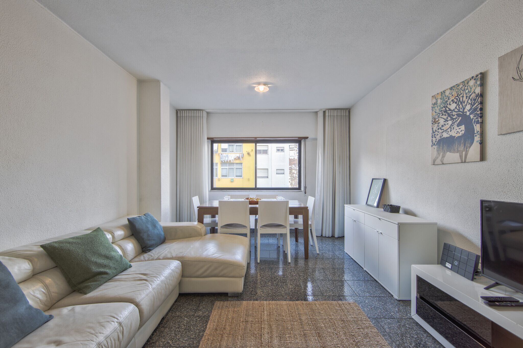 Un salon moderne avec un canapé, une table à manger et un téléviseur.