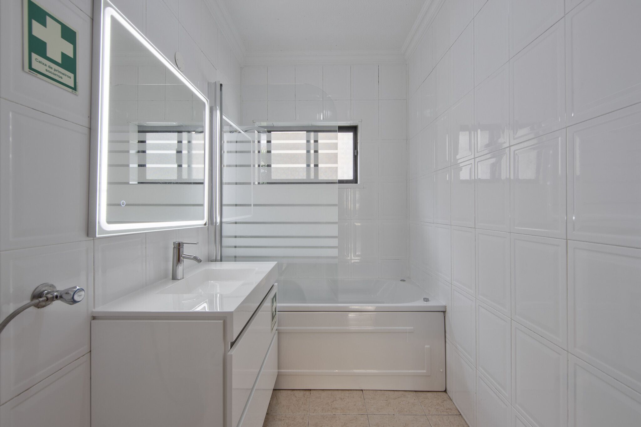A modern bathroom with a white sink, a mirror, and a bathtub.