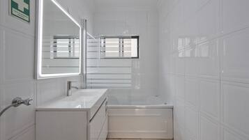 A modern bathroom with a white sink, a mirror, and a bathtub.