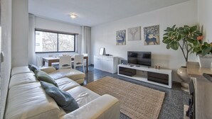 Een moderne woonkamer met een bank, televisie en kunst aan de muur.