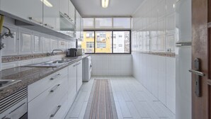 Een moderne keuken met witte kastjes, een granieten aanrechtblad en een ingebouwde vaatwasser.