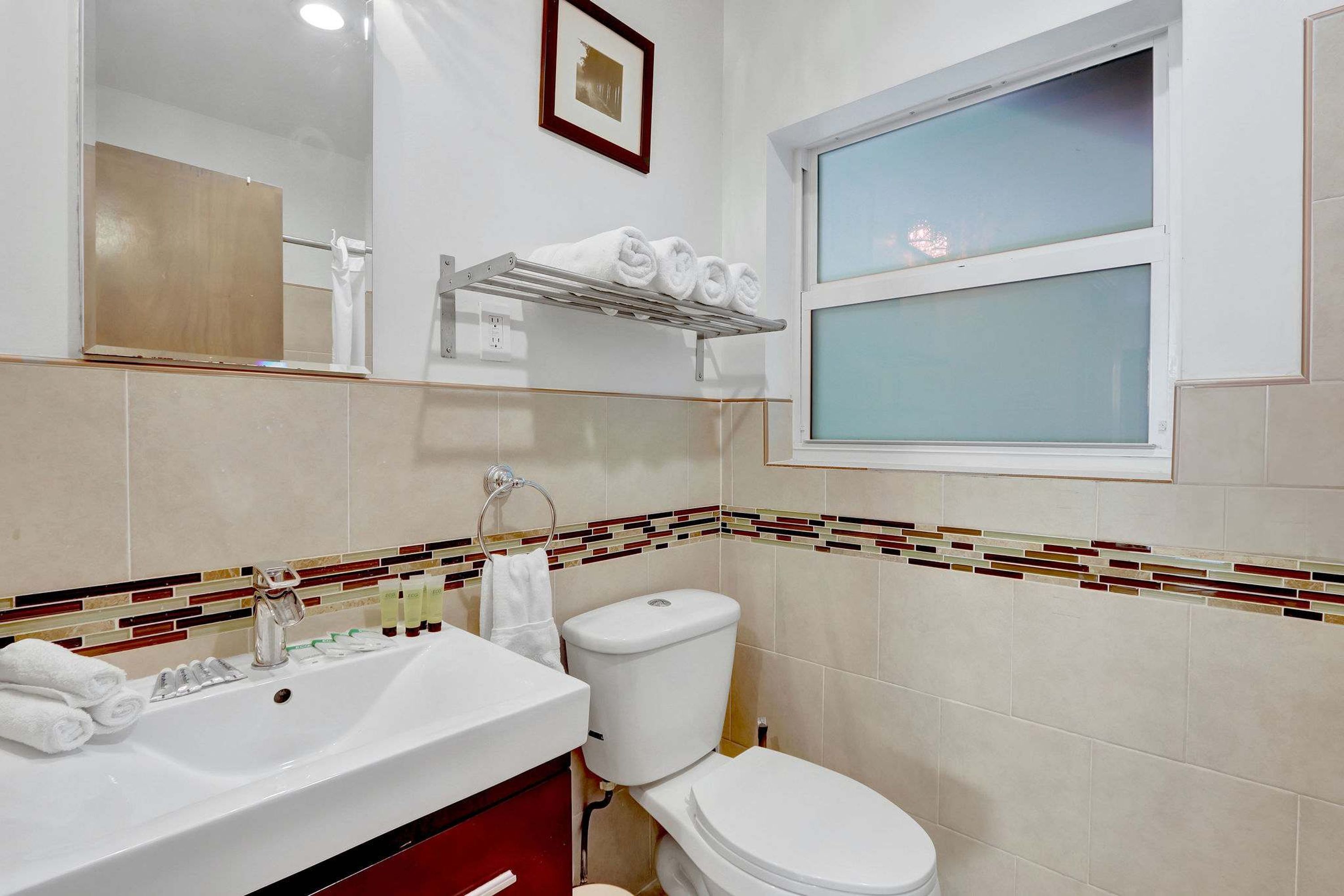 A bathroom with a white sink, a toilet, and a window.