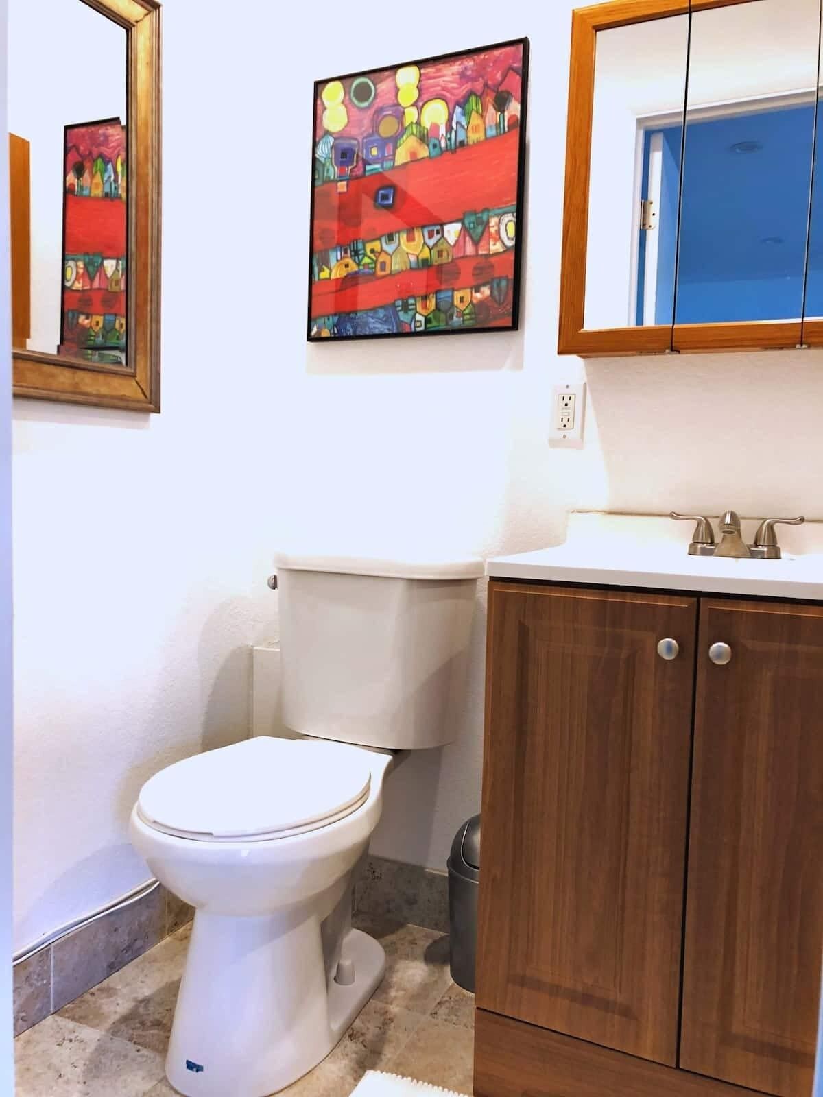 A bathroom with a white toilet, wooden cabinets, and a mirror above the sink.