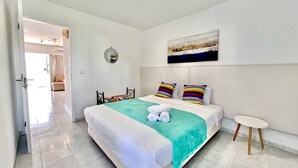 A modern hotel room with a large bed, a small round table, and a view of the hallway. - Vilamoura SEA Village 2 by Homing (Loulé)