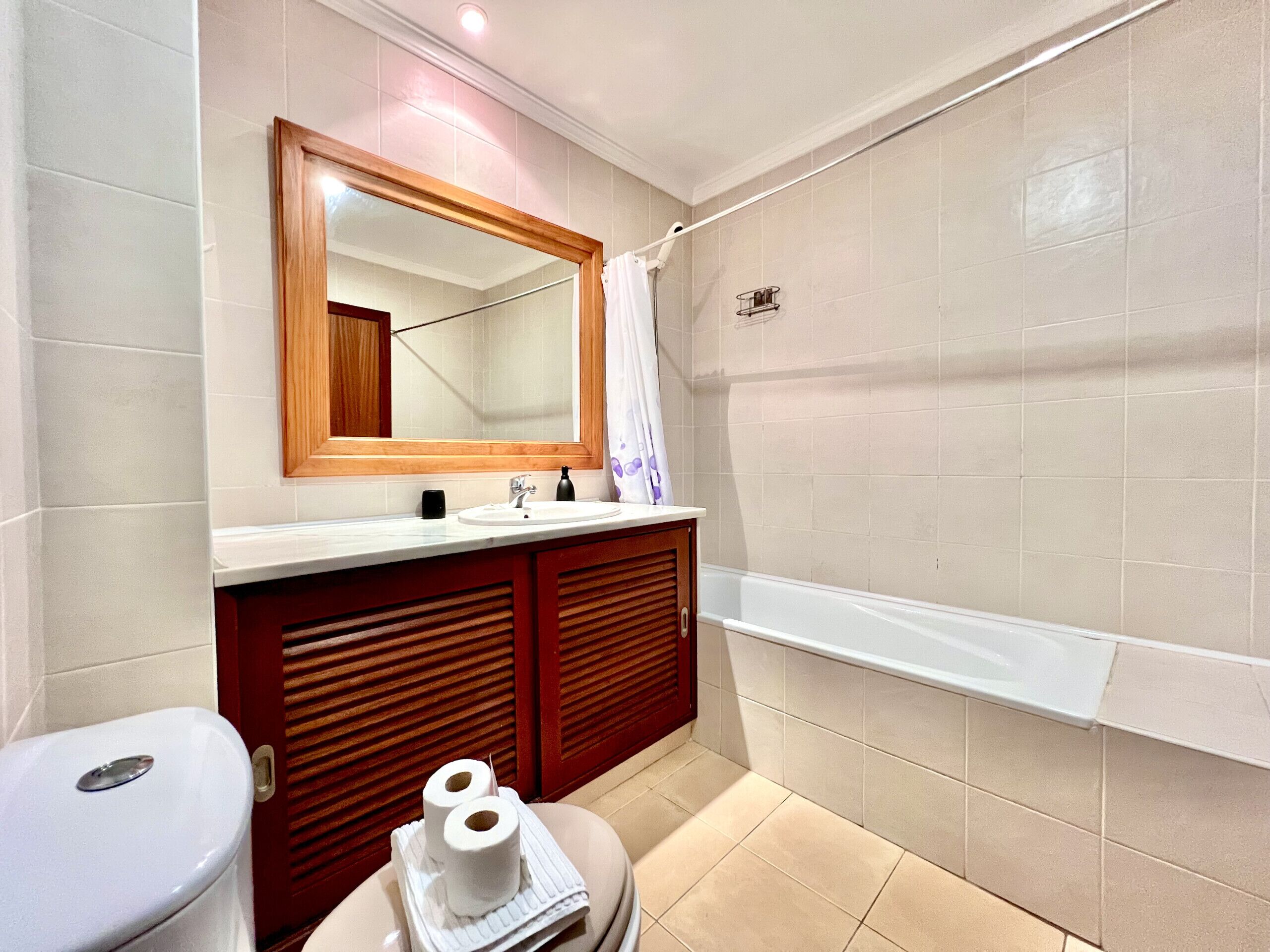 A bathroom with a toilet, sink, mirror, and bathtub.