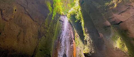 A waterfall in a natural setting with rocky walls and a pool at the base.