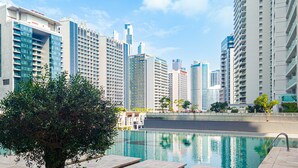 A modern hotel with a pool, surrounded by high-rise buildings and greenery. - LUX The Majestine Studio (Dubai)