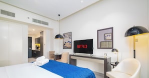 Een moderne hotelkamer met een groot bed, een bureau met een computer, een televisie en een stoel.
