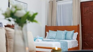 A neatly made bed with light blue bedding, a wooden headboard, and a vase with white flowers on a bedside table.