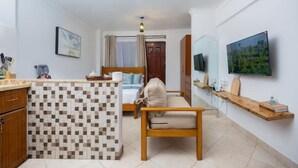 A hotel room with a bed, a desk, a chair, a TV, and a bathroom.