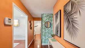 Un couloir doté d’un plancher en bois, d’une porte blanche et d’un système de sécurité fixé au mur.