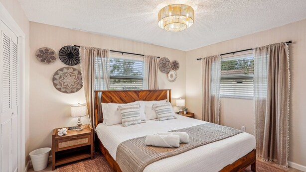Une chambre à coucher bien aménagée, avec un lit en bois, des lampes de chevet, des œuvres d’art décoratives au mur et un luminaire au plafond.