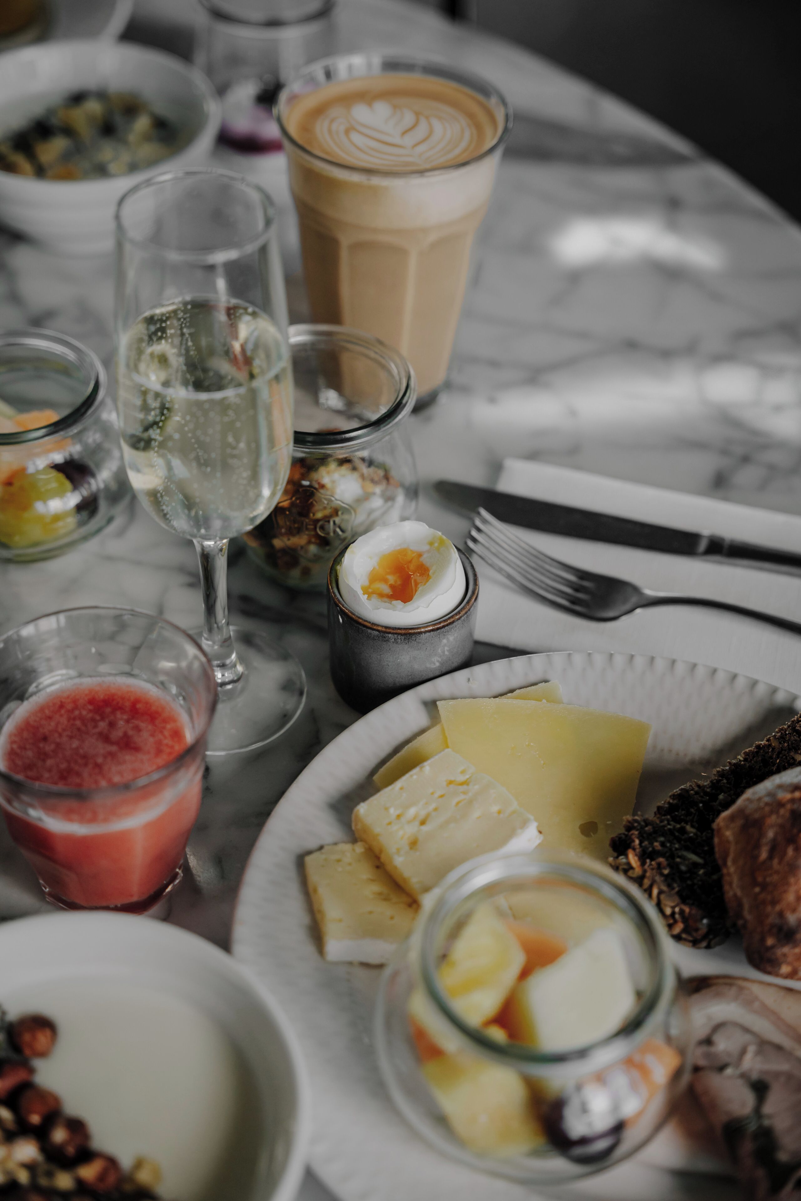 A table with various food items and drinks, including cheese, nuts, and a glass of coffee.