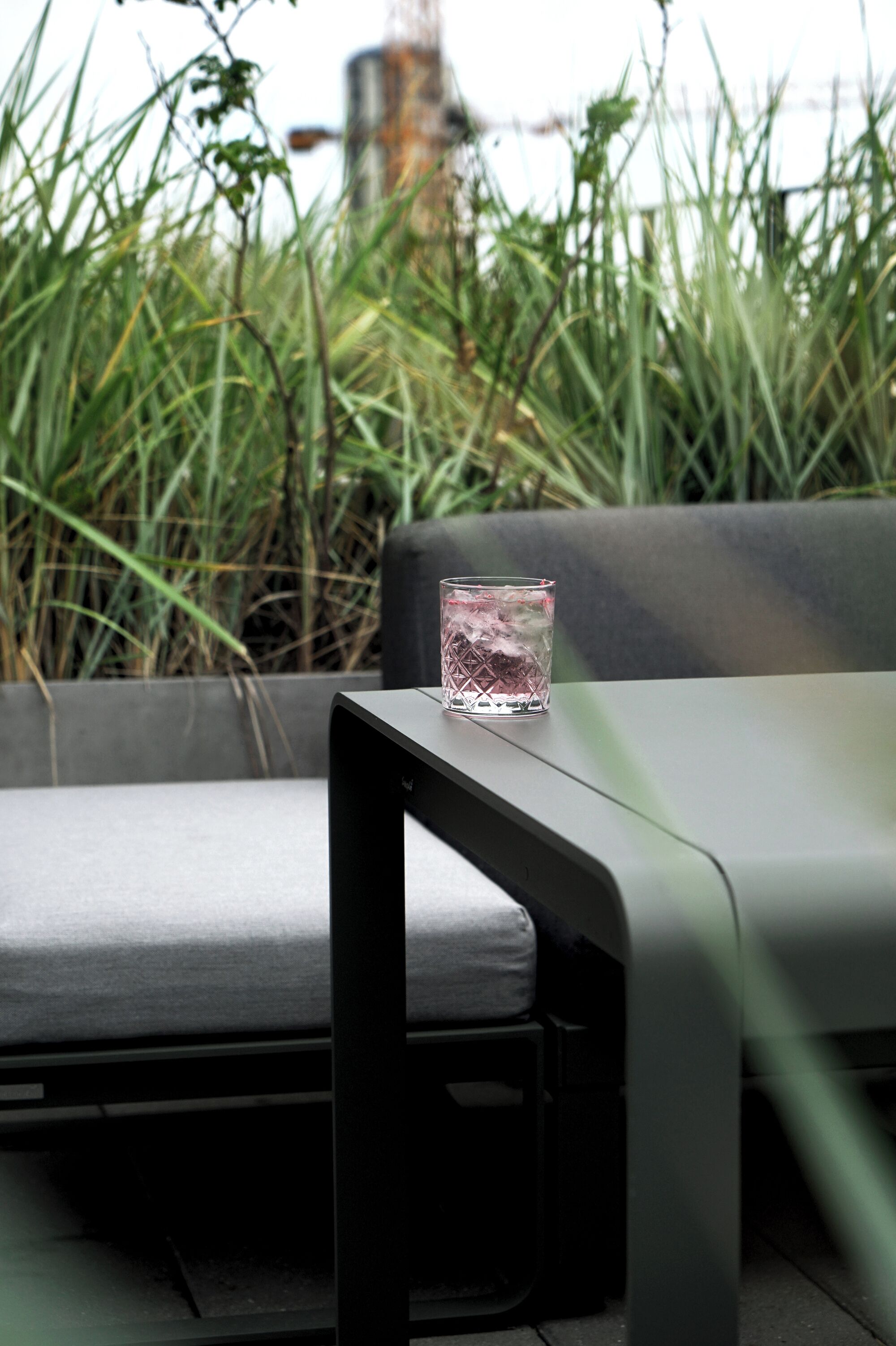 Un espace extérieur moderne, aménagé avec une table en verre et un banc rembourré.