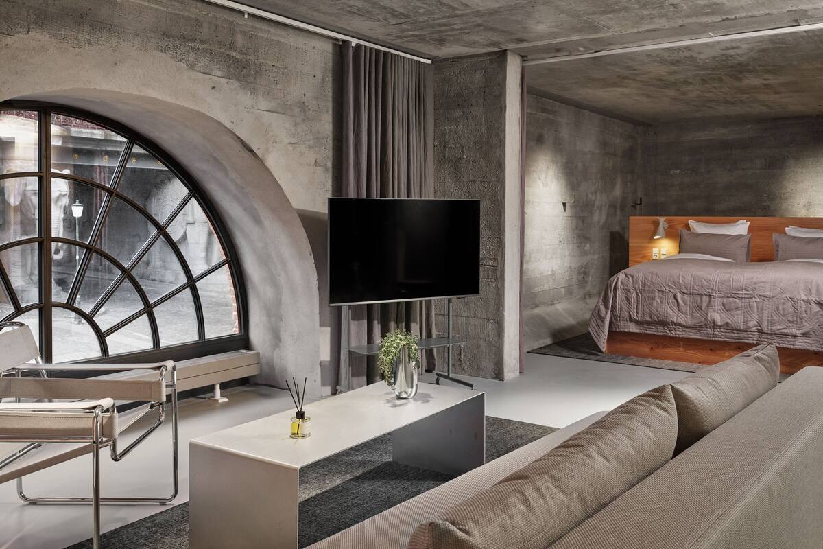 Une chambre moderne dotée d’une grande fenêtre, d’un téléviseur à écran plat, d’un lit et d’un design minimaliste.