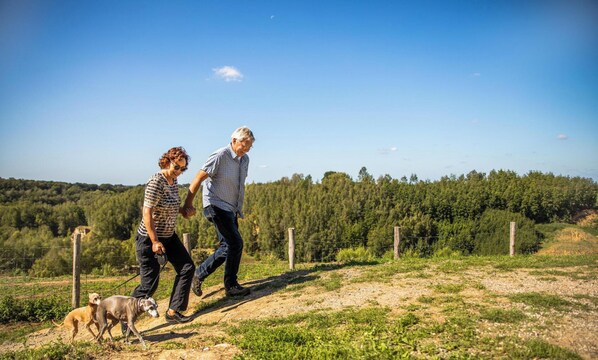 Two people walking a dog on a dirt path with a forest in the background. - Holiday Home Bemelen Near Nature Reserve (Bemelen)