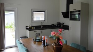 A modern kitchen with a dining area, a window, and a built-in oven. - Holiday Home Bemelen Near Nature Reserve (Bemelen)