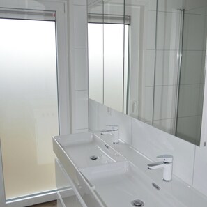 A modern bathroom with a large mirror, a white sink, and a shower area. - Holiday Home Bemelen Near Nature Reserve (Bemelen)