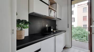Studio, balkon | Privékeuken | Een koelkast, een kookplaat, kookgerei, borden en bestek, een eettafel