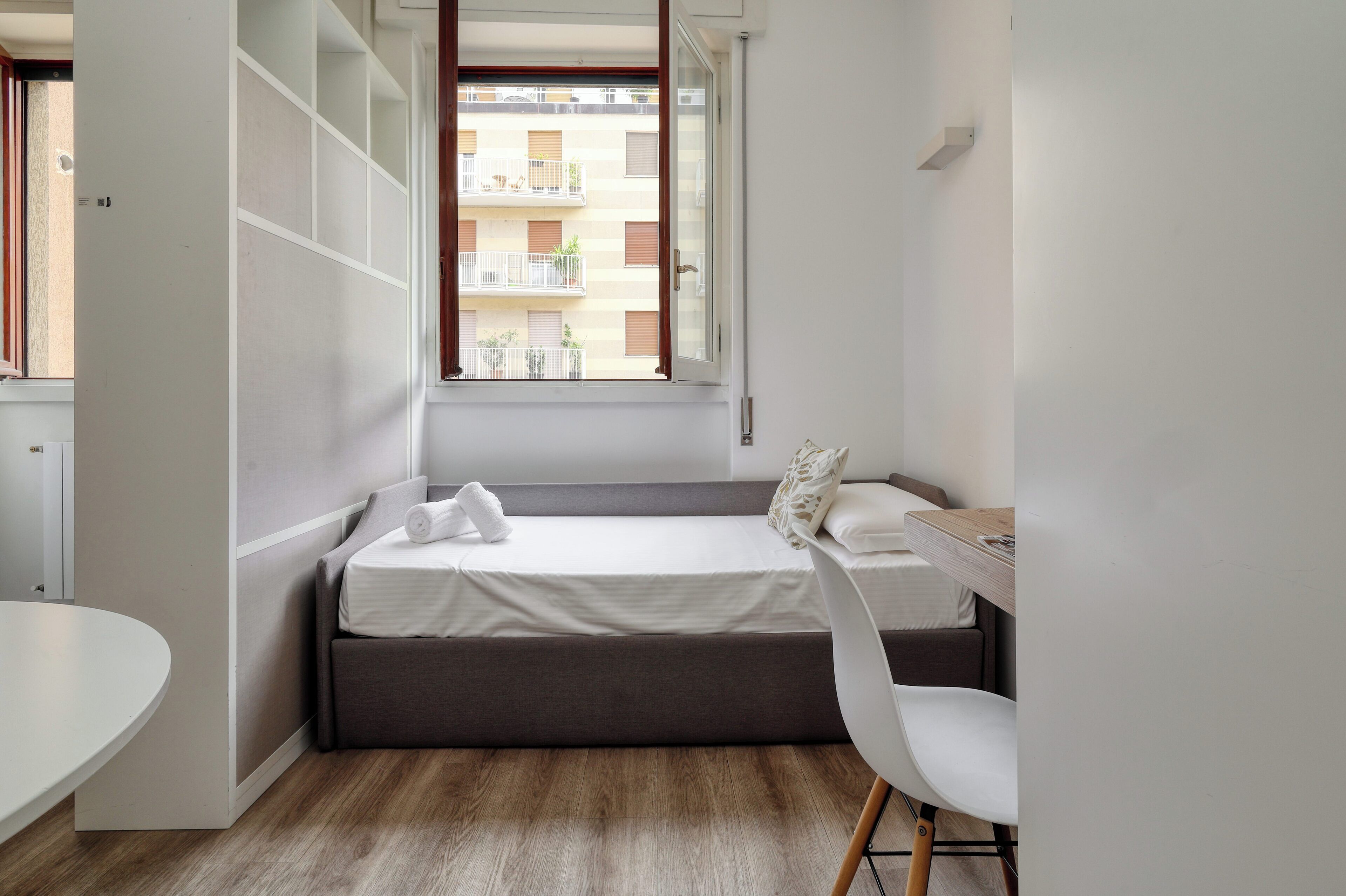 A compact bedroom with a bed, a desk, and a chair.