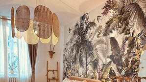 Un dormitorio con cama, escritorio, silla, alfombra tejida y un mural en la pared.