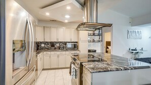 A modern kitchen with stainless steel appliances, a marble countertop, and white cabinetry. - 2 Mi to Golfing: Chic & Cozy Retreat in Lakeland! (Lakeland)