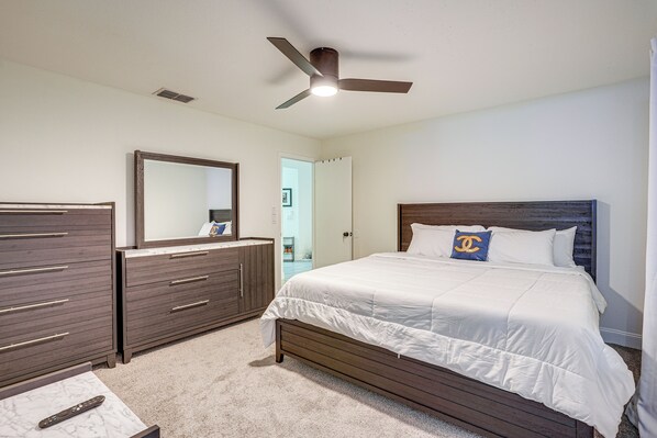 Un dormitorio con cama, cómoda, espejo y ventilador de techo.