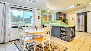 Eine moderne Küche mit Essbereich, ausgestattet mit einer großen Kochinsel, einem Kühlschrank und Blick ins Freie.
