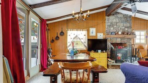 A cozy cabin interior with a stone fireplace, wooden dining table, and benches. - Hike, Ski & Unwind: Cabin w/ Deck in Chester! (Chester)