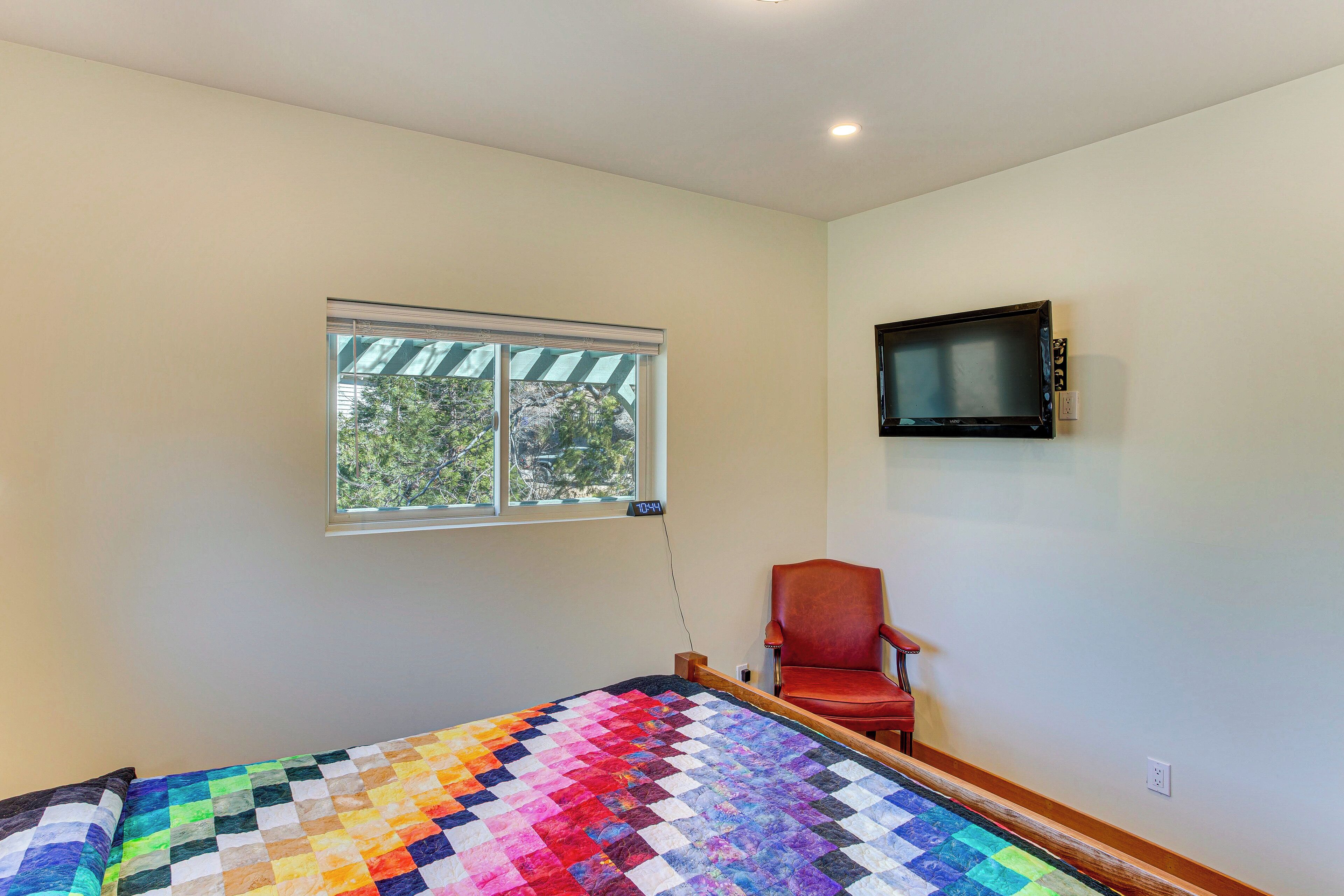 A room with a bed, a window, a television, and a chair.