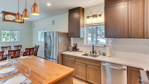 A modern kitchen with wooden cabinets, stainless steel appliances, and pendant lighting. - Game Room & Deck: Pet-friendly Lake Arrowhead Home (Lake Arrowhead)