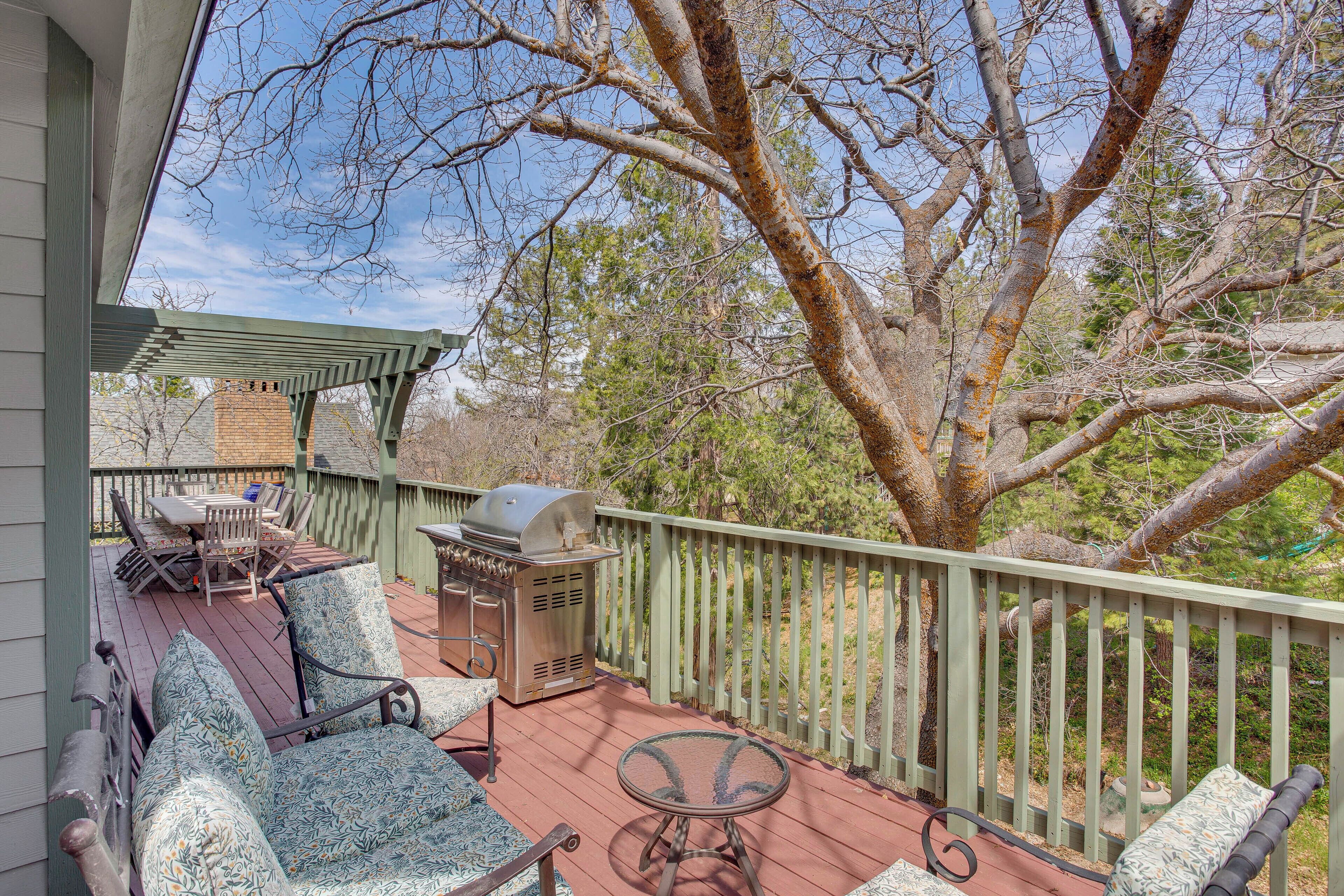 A covered outdoor deck with a grill, chairs, and a table.