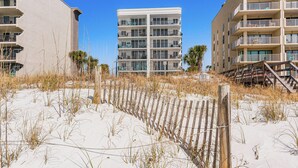 A beachfront hotel with multiple balconies and a sandy beach in the foreground. - Waterfront Fort Walton Beach Condo: Pool Access! (Fort Walton Beach)