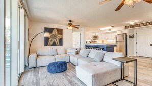 A modern living room with a sectional sofa, a blue ottoman, and a small side table. - Waterfront Fort Walton Beach Condo: Pool Access! (Fort Walton Beach)