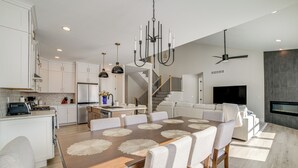 Una cocina moderna con armarios blancos, una mesa de comedor de madera con individuales, y un horno empotrado.