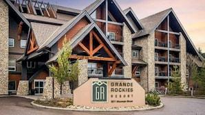 A multi-story hotel with a stone facade, wooden accents, and a prominent sign for Grande Rockies Resort. - Rockies Hideaway - Pool, Waterslide & Hot Tub (Canmore)