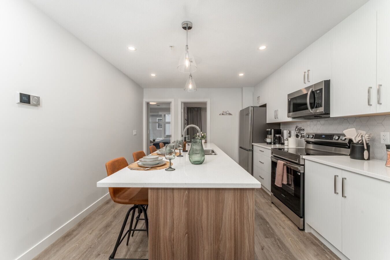 A modern kitchen with white cabinetry, stainless steel appliances, and a central island with seating.