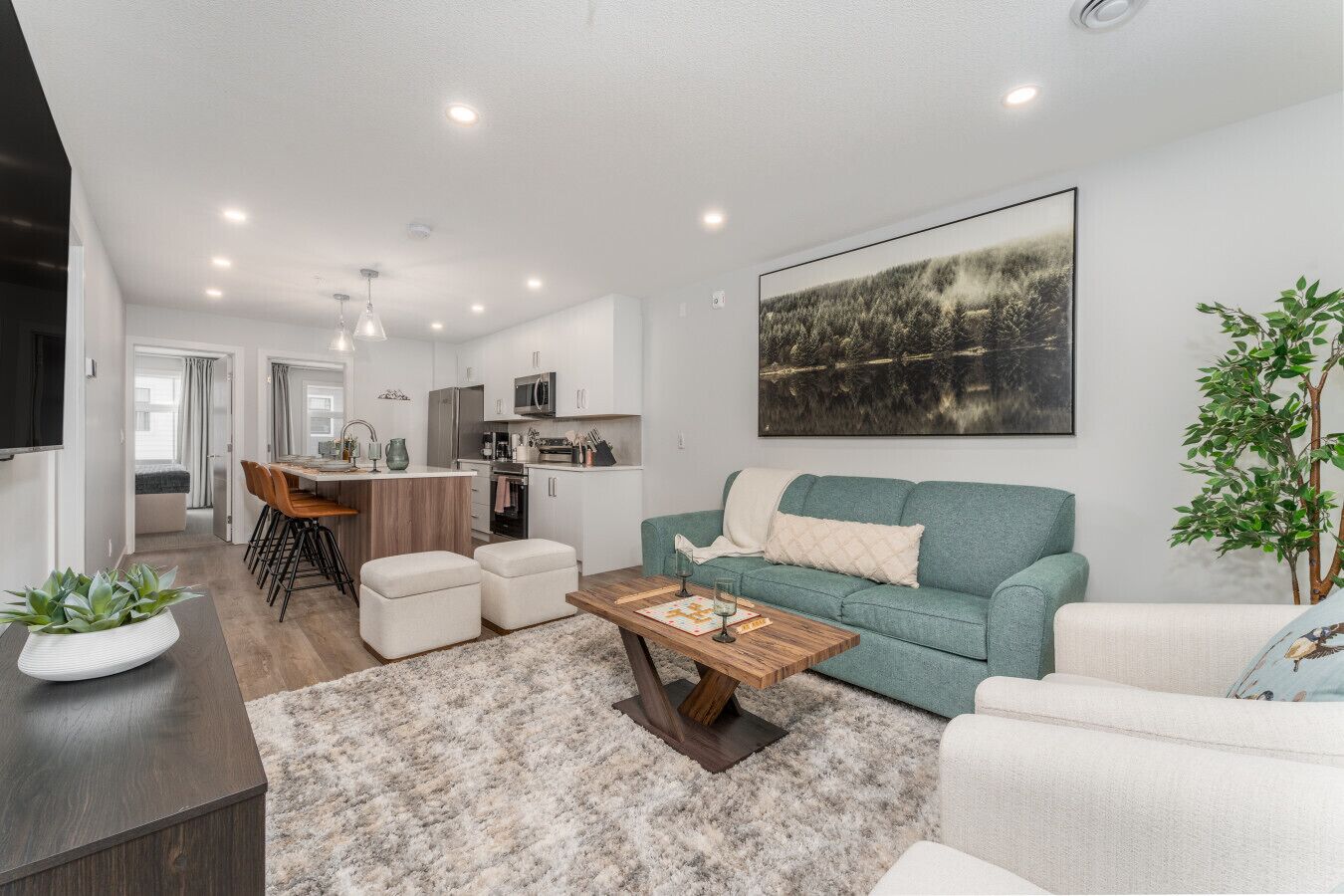 Un salon moderne avec un canapé, une table basse et un coin repas comprenant des chaises, et une cuisine en arrière-plan.