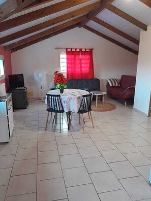 A dining area with a round table, chairs, a sofa, and a TV. - Top of F2 villa in the countryside (Capesterre-Belle-Eau)