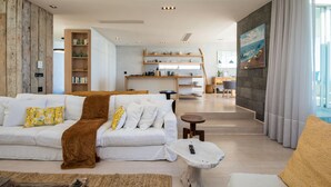 A modern living room with a sofa, coffee table, and a dining area in the background. - Ethereal 4bed Camps Bay Villa Atlantic Reflection (Cape Town)